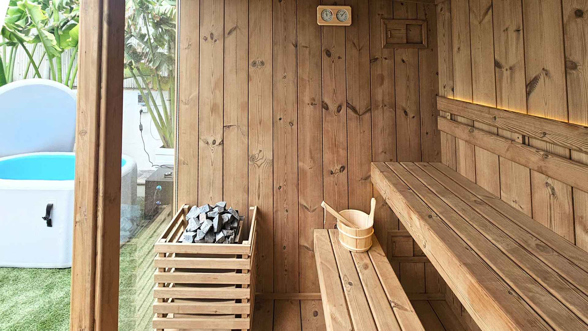 Outdoor timber sauna with heater stones and wooden bucket